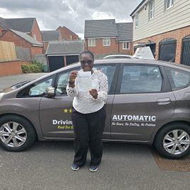 Gladys, a driving student, smiling after passing her driving test with only one minor fault.