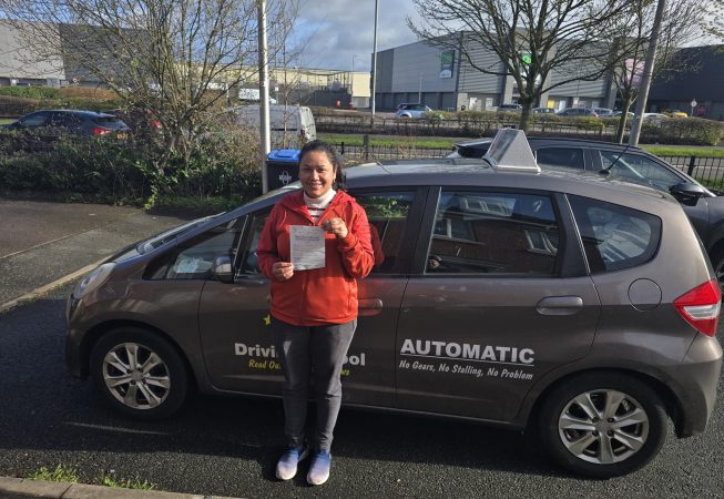 Ritu smiling beside a car after passing her driving test on her first attempt.
